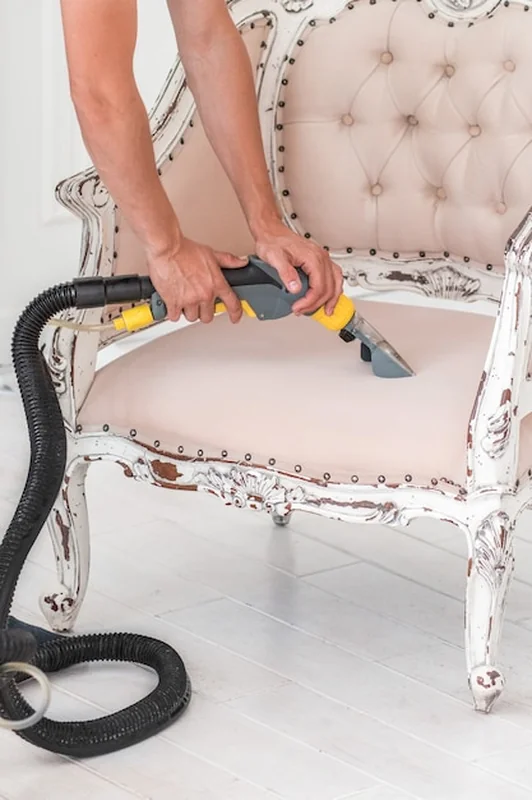 Ręka pracownika pralni czyści sofę metodą ekstrakcji