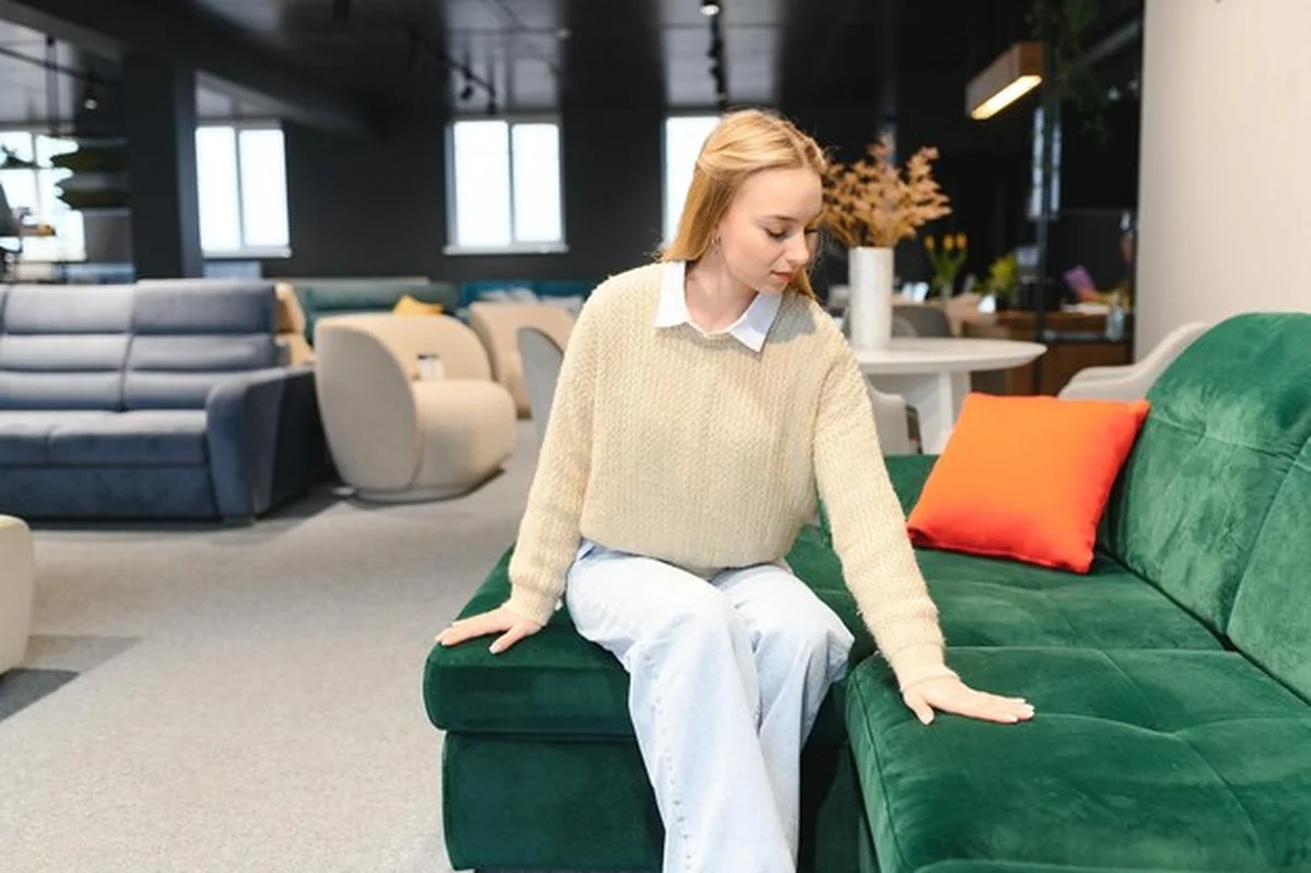 Młoda kobieta testuje kanapę w sklepie meblowym