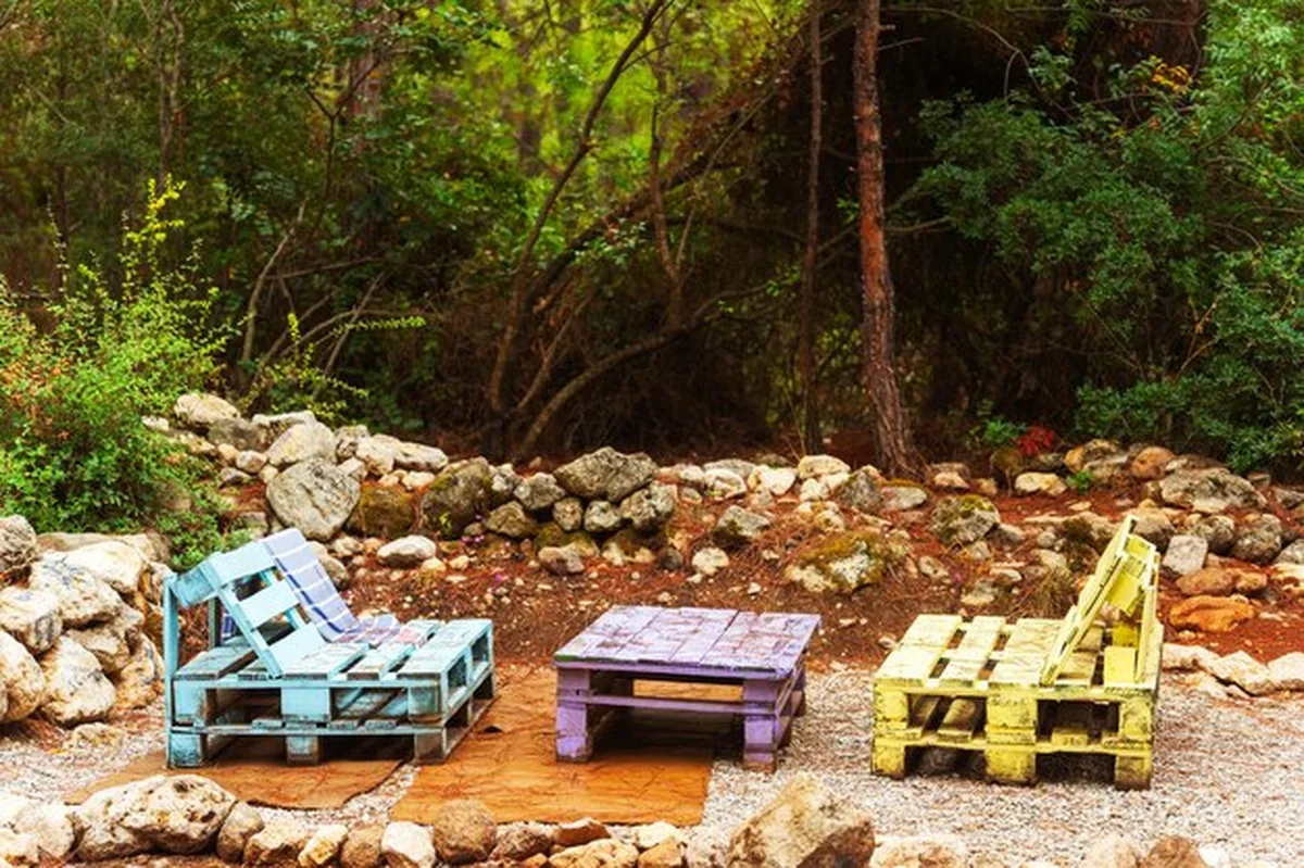 Dwa kolorowe krzesła i stół z drewnianych palet