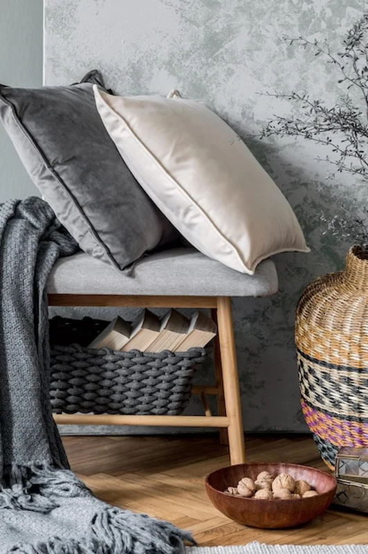 Stylowa kompozycja wnętrza salonu z eleganckimi poduszkami i szarą ścianą w stylu skandynawskim