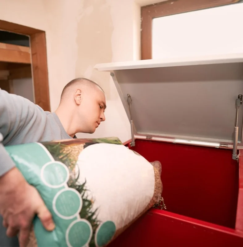 Mężczyzna korzystający z pieca grzewczego na pelety w kotłowni