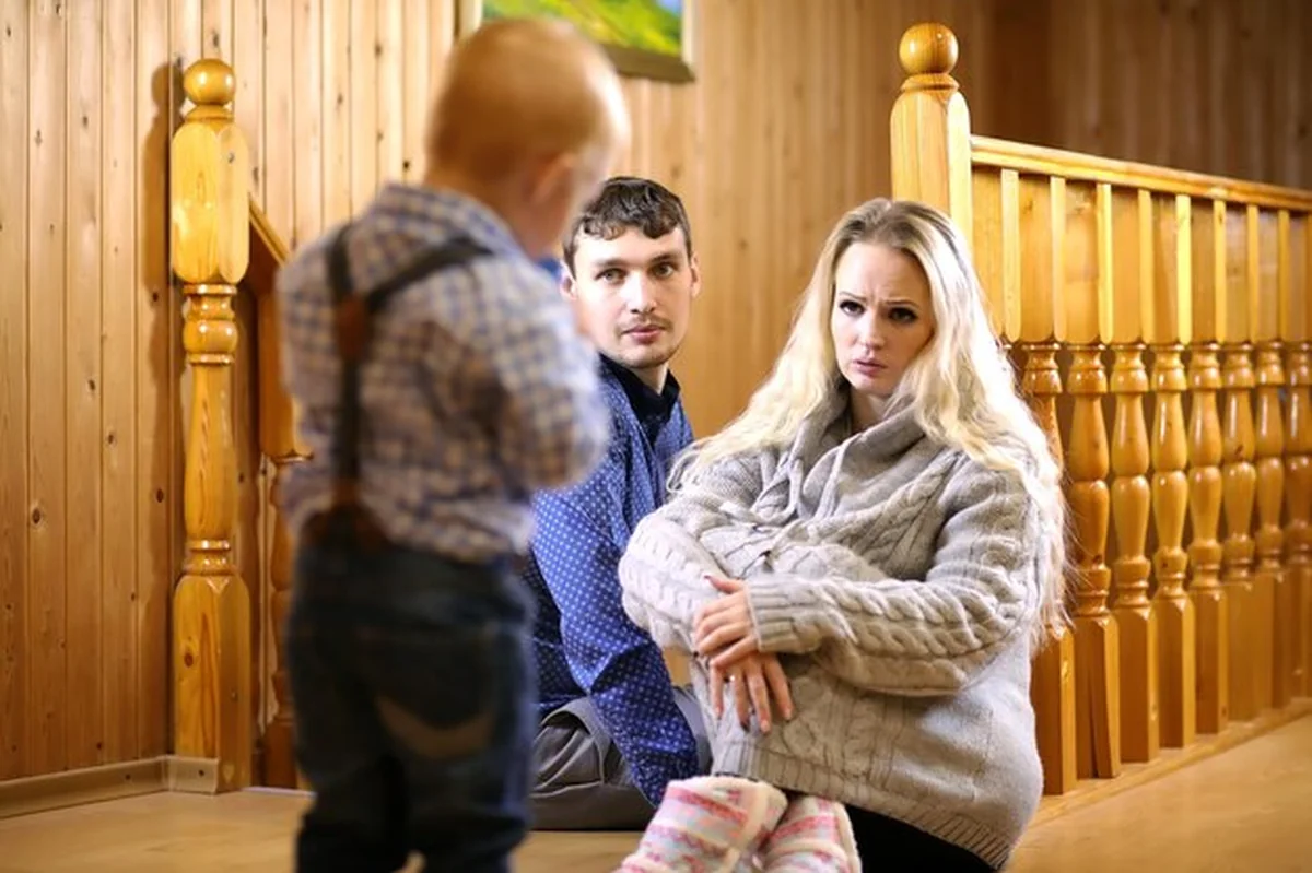 Rodzic z dzieckiem siedzącym na podłodze obok drewnianej balustrady schodów