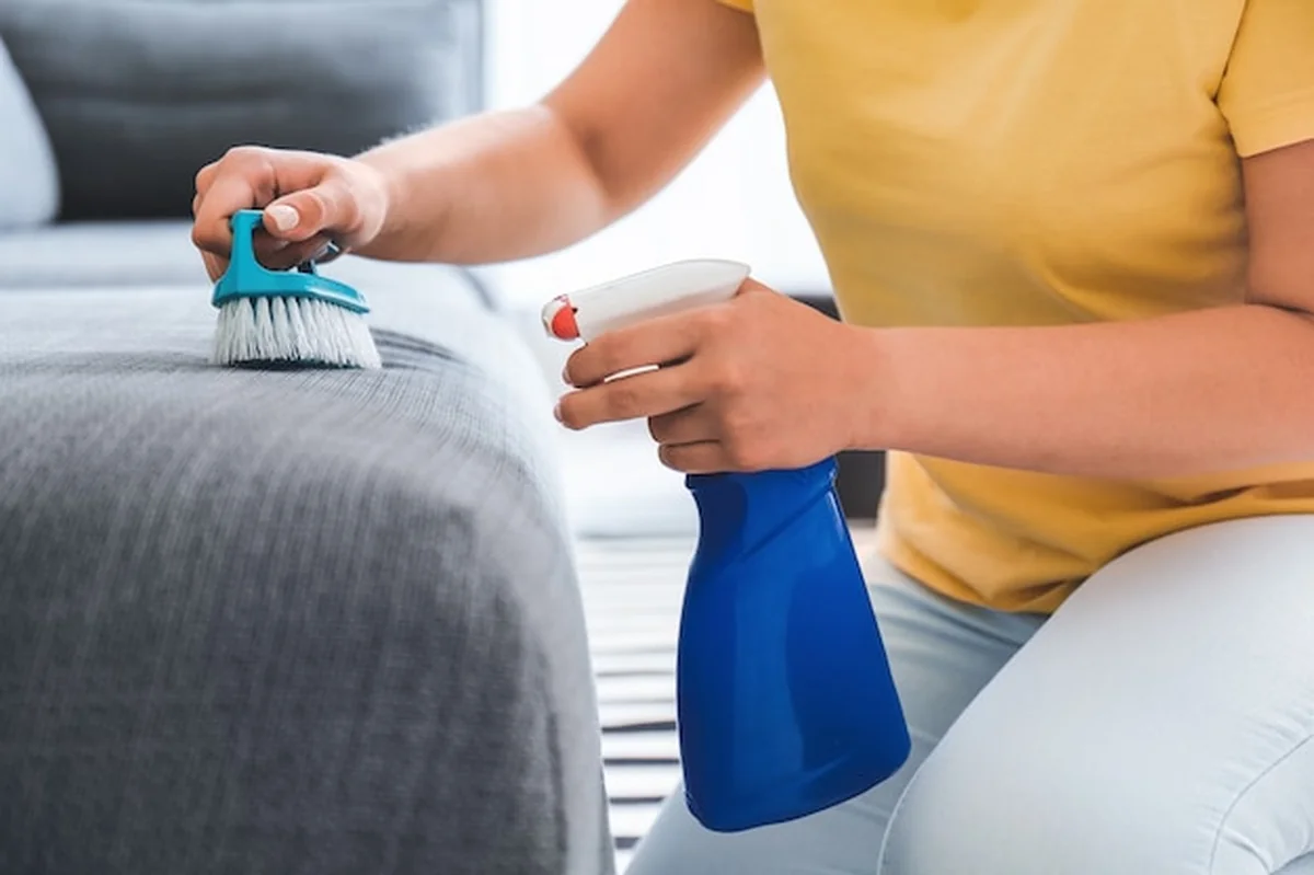 Kobieta czyści skórzaną sofę w domu