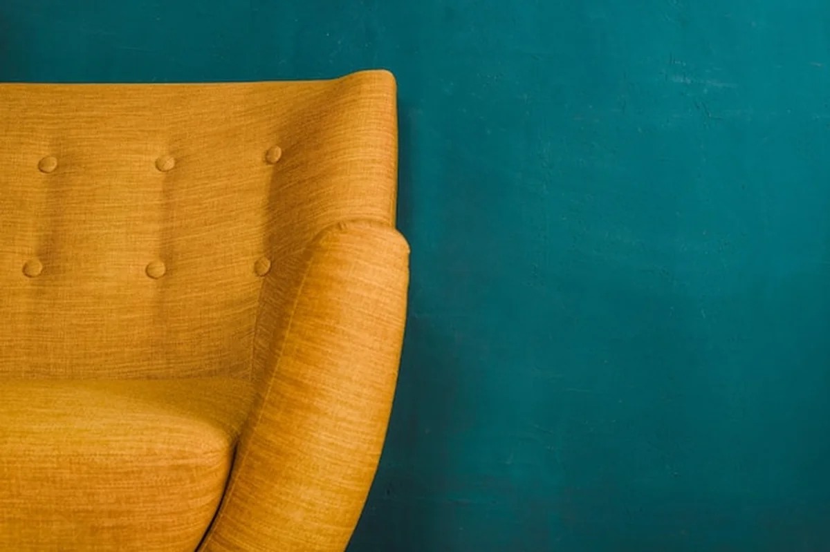 Żółta sofa vintage na ciemnozielonej ścianie z teksturą