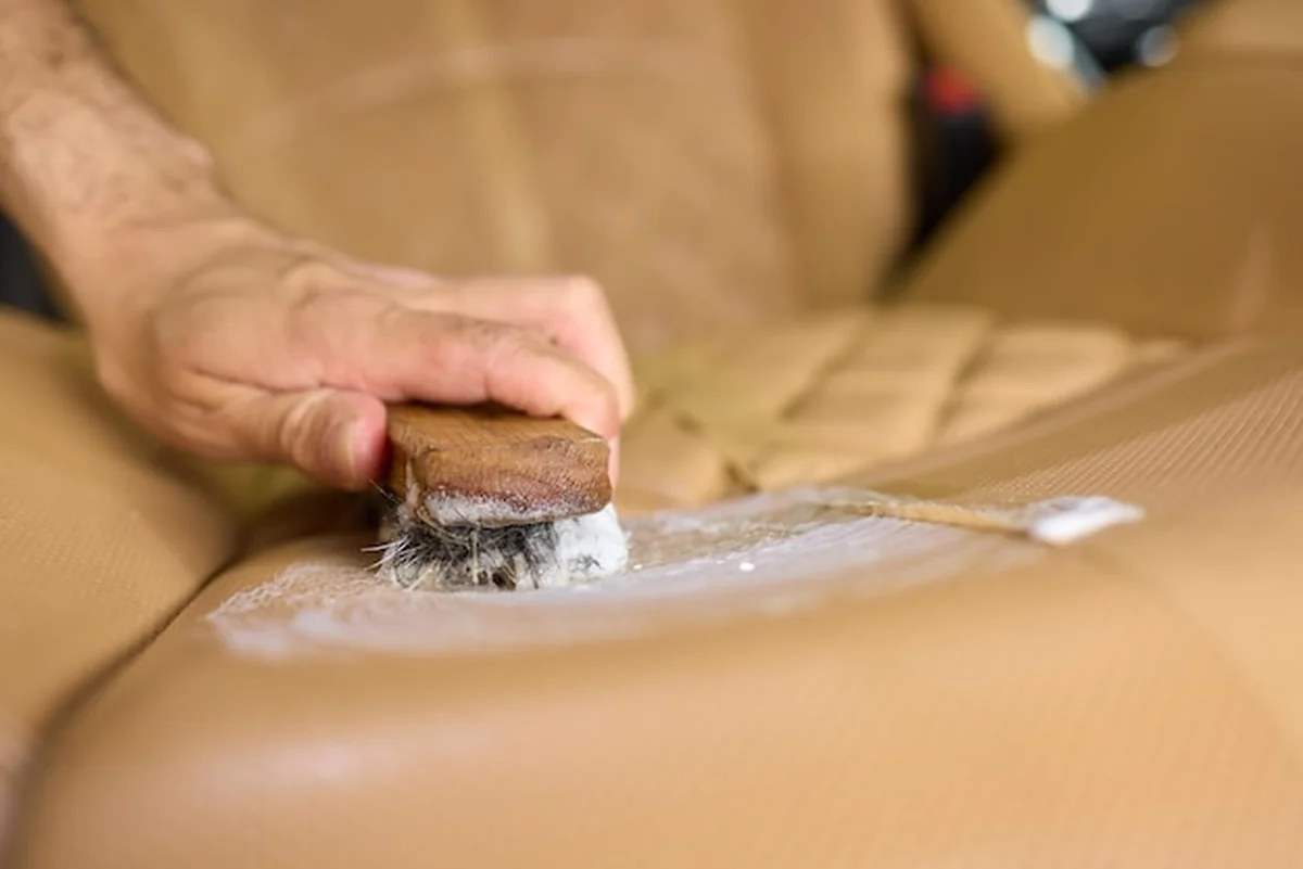 Czyste skórzane fotele samochodowe z plastikową pokrywą i szczotką do konserwacji