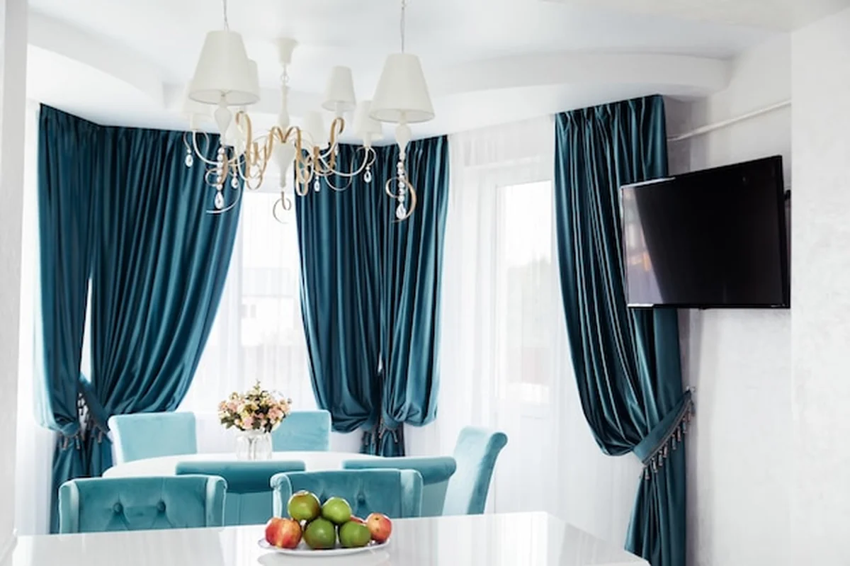 Elegancka jadalnia z niebieskimi zasłonami, żyrandolem i telewizorem
