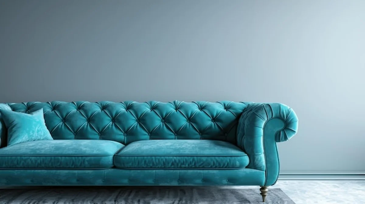 Turkusowa kanapa w przestronnym pokoju obok pustej białej ściany