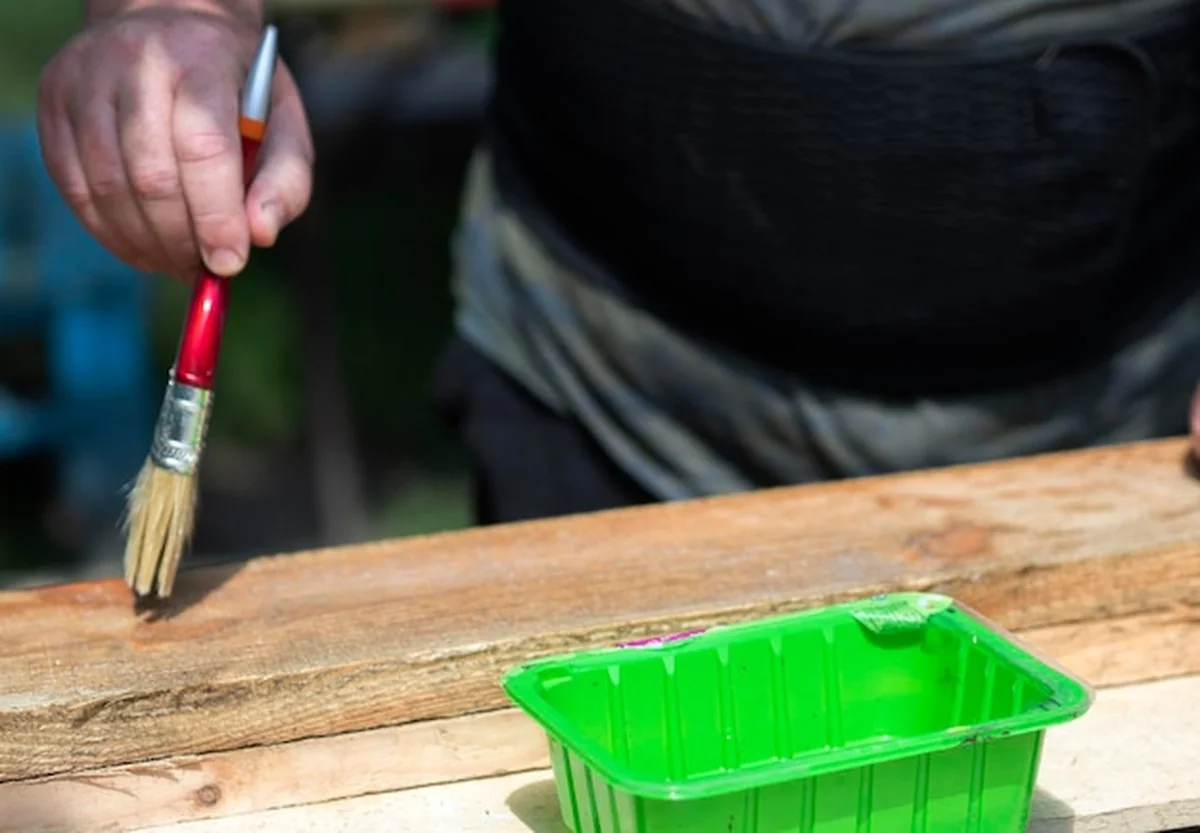 Mężczyzna kryje deski białą substancją szczotką