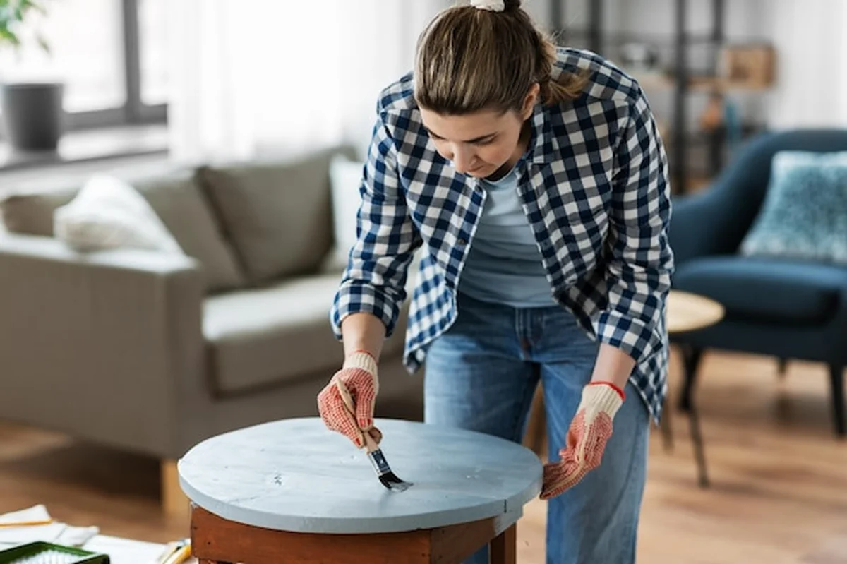 Kobieta malująca drewniany stół na szaro