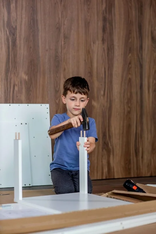 Chłopiec montuje meble w domu