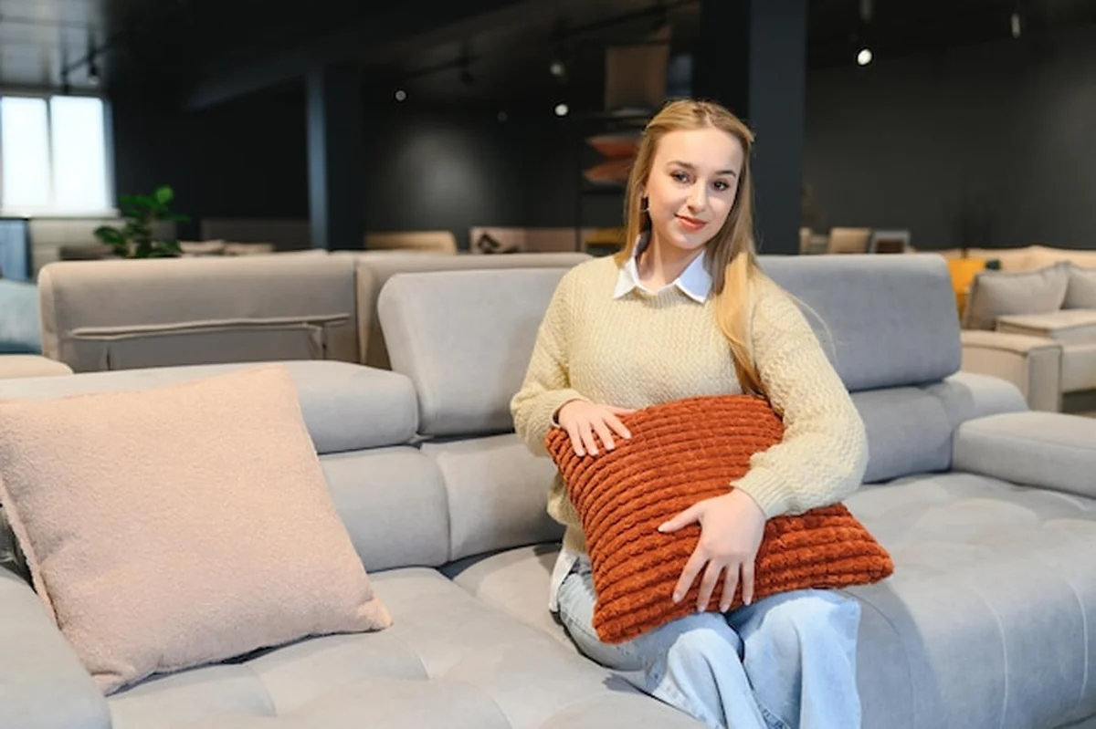 Młoda kobieta wybiera kanapę w sklepie z meblami