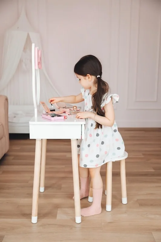 Dziewczynka w lustrze czyszcząca małą dziewczynkę siedzącą przy stoliku dla dzieci