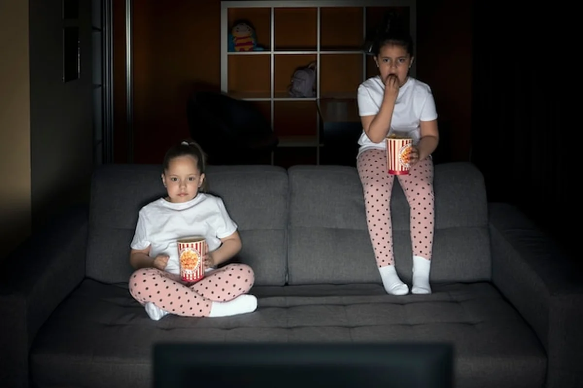 Dwie siostry oglądają program telewizyjny na kanapie