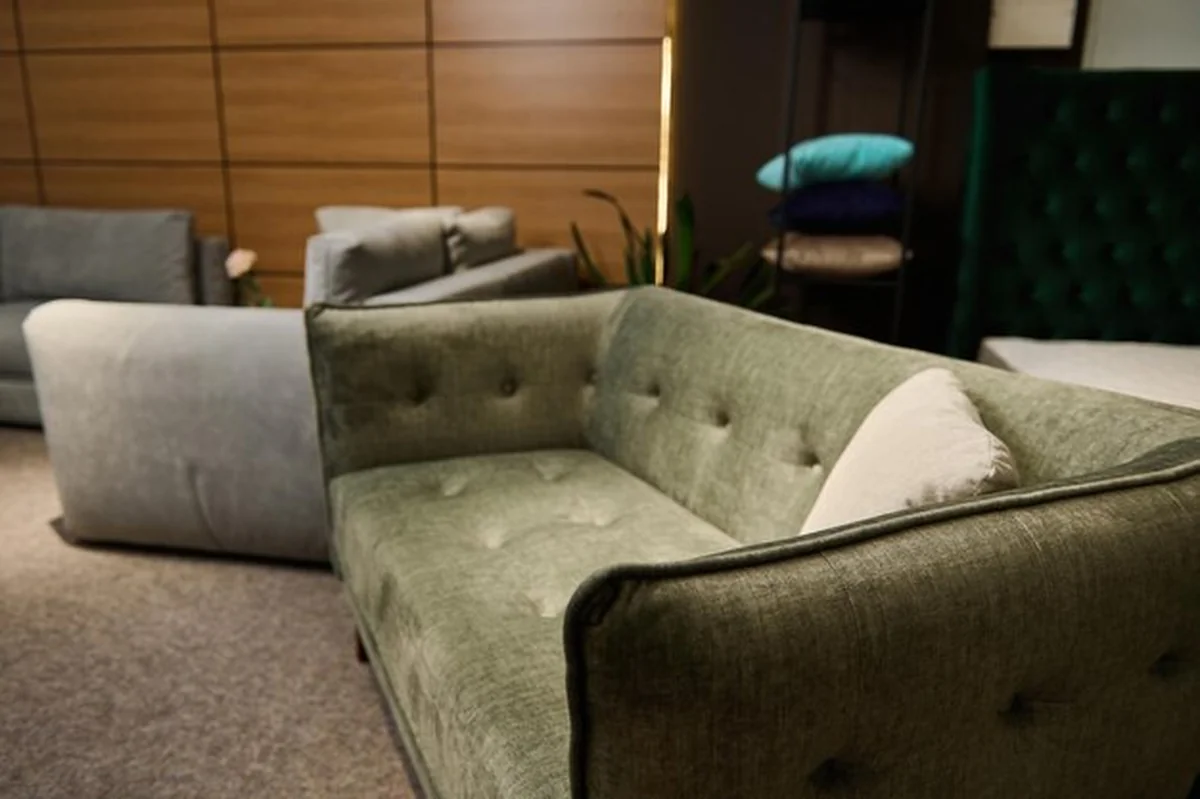Nowoczesna zielona sofa z poduszkami w salonie meblowym