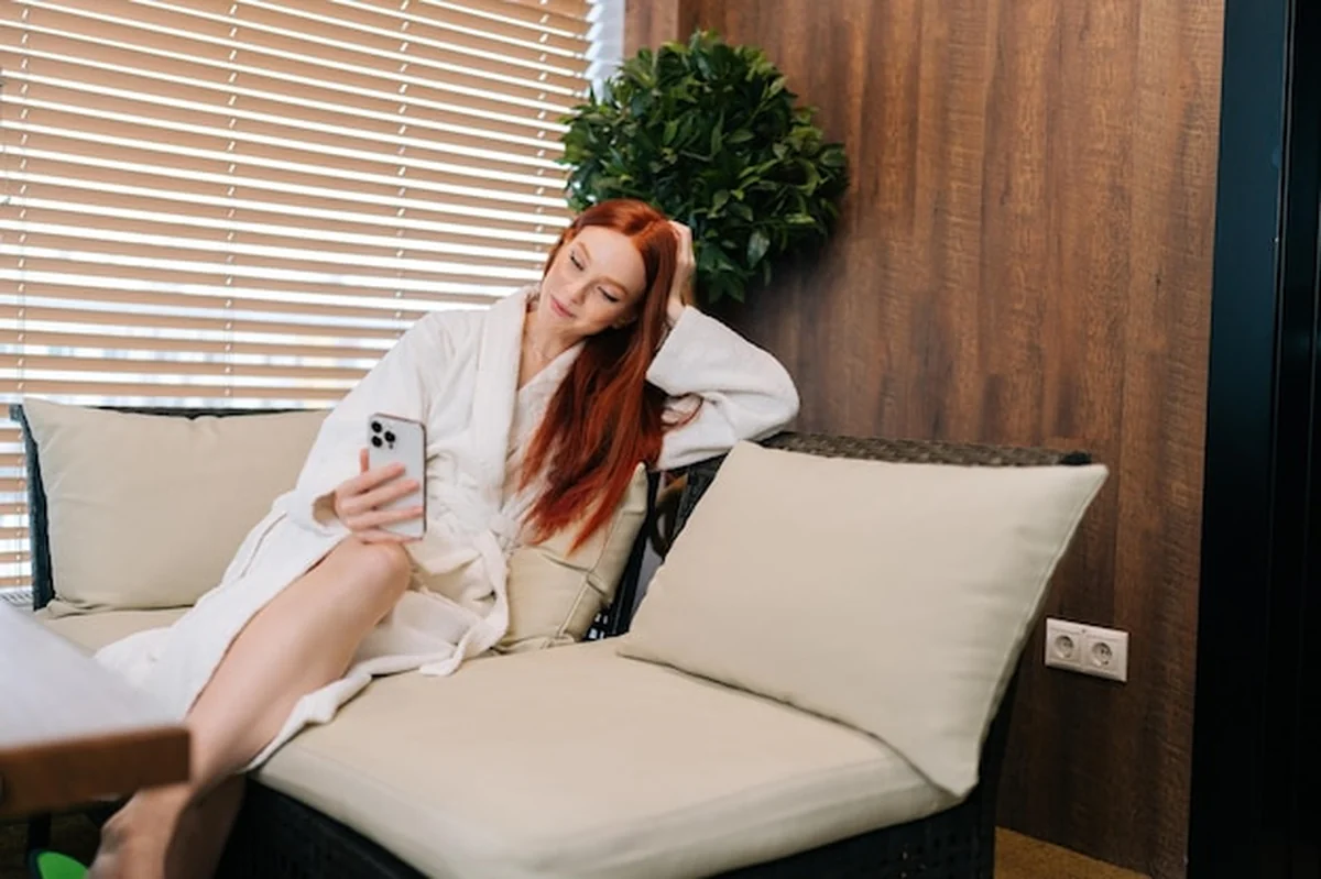 Młoda kobieta rozmawia przez wideo na sofie w salonie spa