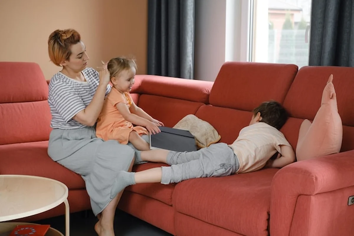 Matka opiekująca się dwójką dzieci na dużej sofie