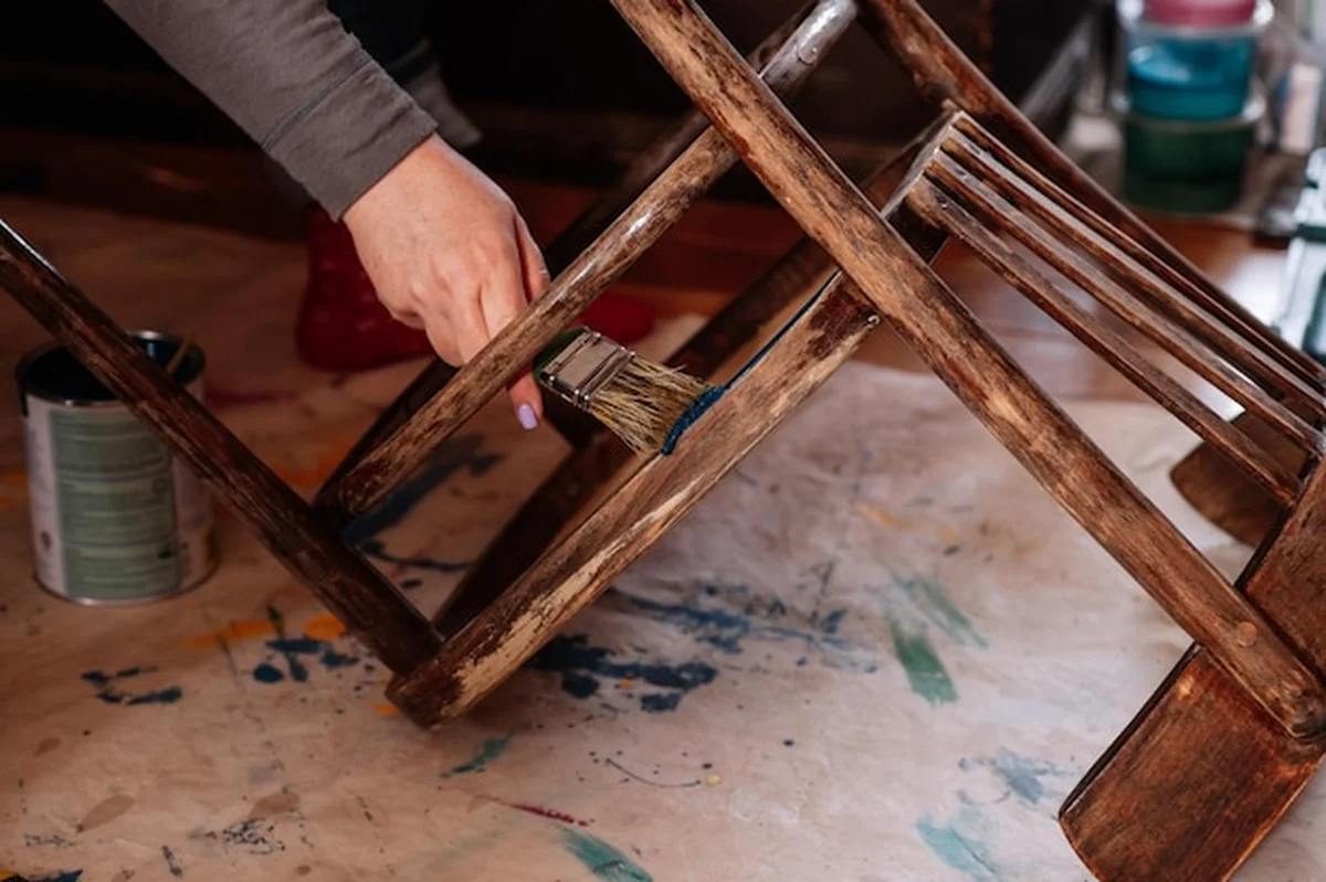 Ręka malująca stary krzesło pędzlem w domowym warsztacie