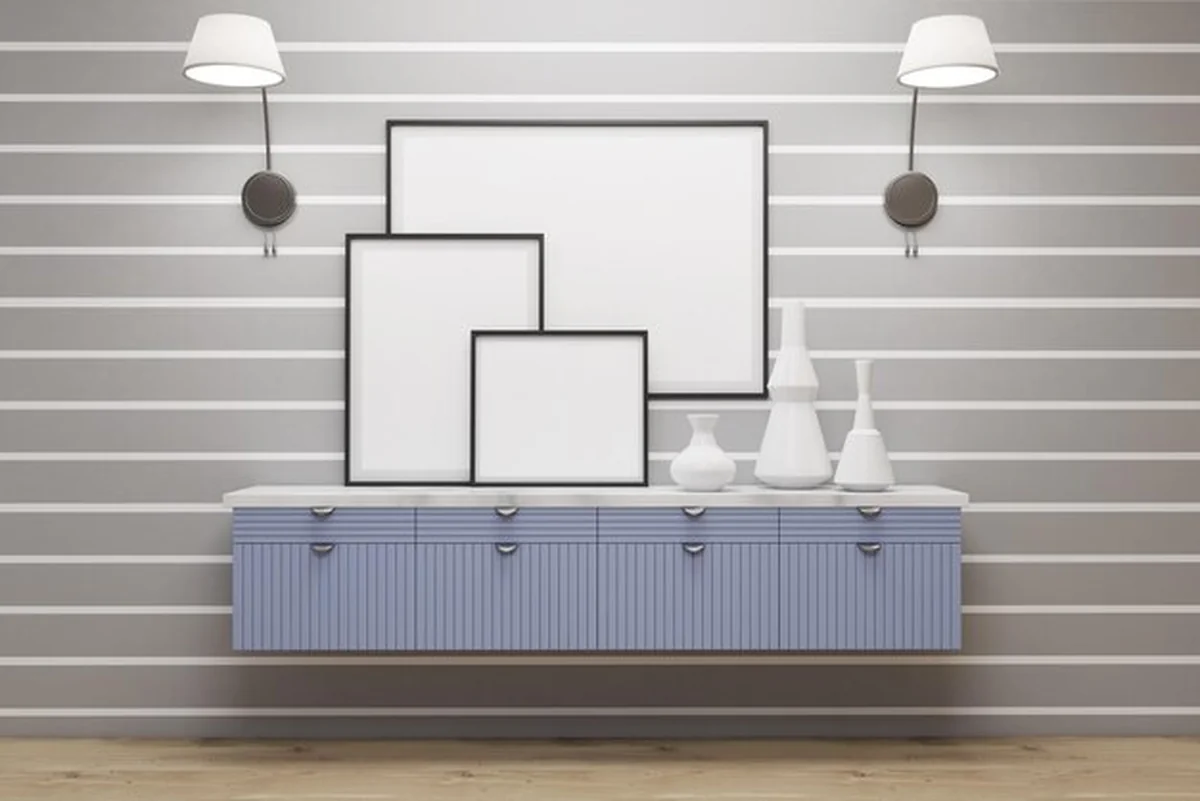 Plakaty w ramkach na białych paskach na szarej ścianie