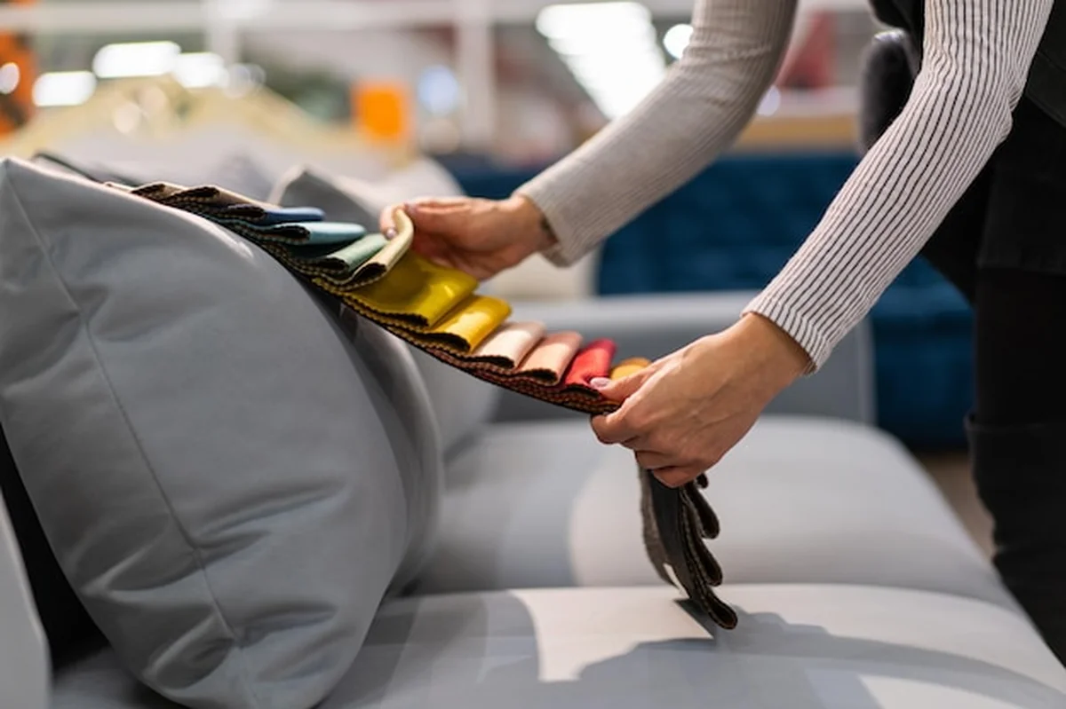 Kobieta wybiera tkaninę na sofie, a młoda kobieta ogląda próbki tkanek